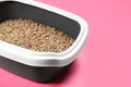 Cat litter tray with filler on pink background, closeup