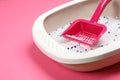 Cat litter tray with filler and scoop on pink background, closeup