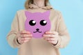 Cat muzzle in the hands of caucasian woman. Blue background