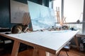 cat sits on drafting table, sketching out the design for a futuristic skyscraper