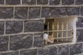 Cat watching through bars in traditional basalt building