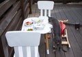 Cat on a wooden veranda near a white table with chairs