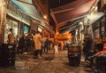 Visitors of night bars walking, talking and drinking beer outside, on dark city street