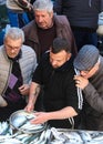Catania, Sicily, Italy - Apr 10th 2019: Fishmonger selling fresh fish on traditional fish market. Older man, demanding customer,