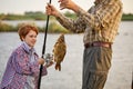 Catch of the day. Cropped grandfather and child boy fishing while on the shore of pond Royalty Free Stock Photo