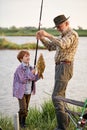 Catch of the day. Happy grandfather and child boy fishing while on the shore of pond Royalty Free Stock Photo