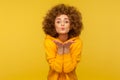 Catch my love kiss! Portrait of curly-haired young woman in urban style hoodie kissing air over palms Royalty Free Stock Photo