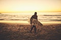 Catch you on the surfy side. a young man carrying a surfboard at the beach.