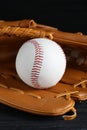 Catcher`s mitt and baseball ball on black background, closeup. Sports game Royalty Free Stock Photo