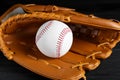 Catcher`s mitt and baseball ball on black background, closeup. Sports game Royalty Free Stock Photo