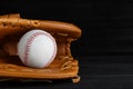 Catcher`s mitt and baseball ball on black background, space for text. Sports game Royalty Free Stock Photo