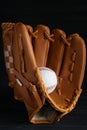 Catcher`s mitt and baseball ball on black background. Sports game Royalty Free Stock Photo