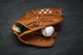 Catcher`s mitt and baseball ball on black slate background, top view. Sports game Royalty Free Stock Photo