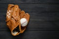 Catcher`s mitt and baseball ball on black wooden table, top view with space for text. Sports game Royalty Free Stock Photo