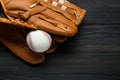 Catcher`s mitt and baseball ball on black wooden table, top view with space for text. Sports game Royalty Free Stock Photo