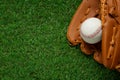 Catcher`s mitt and baseball ball on green grass, top view with space for text. Sports game Royalty Free Stock Photo