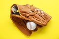 Catcher`s mitt and baseball ball on yellow background, top view. Sports game Royalty Free Stock Photo