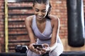 Catching a break between sets. a sporty young woman using a cellphone while taking a break in a gym.