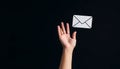 Catching a Digital Message: Hand Reaching for a Floating Envelope Icon against a Black Background Royalty Free Stock Photo