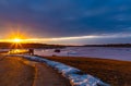 Catching the tail end of winter snow with ice fishing at Golden sunset and blue clouds reflecting on frozen lake. Royalty Free Stock Photo