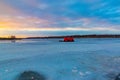 Catching the tail end of winter snow with ice fishing at Golden sunset and blue clouds reflecting on frozen lake. Royalty Free Stock Photo