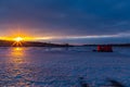 Catching the tail end of winter snow with ice fishing at Golden sunset and blue clouds reflecting on frozen lake. Royalty Free Stock Photo