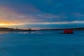 Catching the tail end of winter snow with ice shanty and fishing at Golden sunset and blue clouds reflecting on frozen lake. Royalty Free Stock Photo