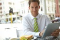 Catching up on emails during lunch. A young businessman working on his digital tablet while sitting at an outdoor cafe.