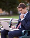 Catching up on emails at the park. a handsome businessman working on his laptop while sitting on a park bench.