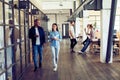 Catching up before meeting. Full length of young modern people in smart casual wear discussing business and smiling Royalty Free Stock Photo