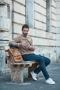 Catching up on some emails. Full length shot of a handsome businessman using his cellphone while sitting on a bench in