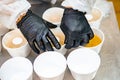 Catering, a cook in the kitchen in a white robe and gloves prepares food in disposable containers