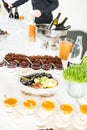 Catering Desserts on Buffet Table with Man Serving Red Wine in the Background