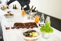 Catering Desserts on Buffet Table with Man Serving Red Wine in the Background