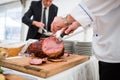 Catering service employee cutting ham Royalty Free Stock Photo