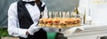 Catering service. Waiter carrying a tray of appetizers. Outdoor party with finger food, mini burgers, sliders. Royalty Free Stock Photo