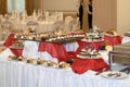 Catering table with lots of sweet snacks, small cakes with cream and chocolate cream in the banquet hall