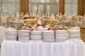 Catering table with lots of white plates and prepared salads in the banquet hall