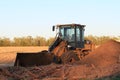 Caterpillar front end loader with a pile of dirt and tree`s out in the country.