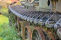 The caterpillar of an old Soviet tank on the background of rusty wheels