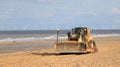 Caterpillar tractor bulldozer on beach with wind turbines