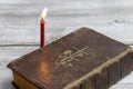 Catholic bible and red church burning candle on wooden background