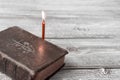 Catholic bible and red church burning candle on wooden background with copy space