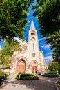 Catholic Cathedral Basilica with a high spire. Landscape against the blue sky. In the foreground are the crowns of trees Royalty Free Stock Photo