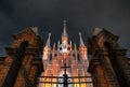 Catholic cathedral in the Gothic style between the brick pillars of the fence with a cross