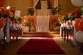 Church decoration on wedding day with flowers and ballons and a red carpet in orange theme and the sunrays falling through