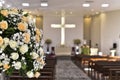 Catholic church prayer altar with flower arrangements and cross in the background Royalty Free Stock Photo
