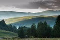 Catholic church tower between pine woods, forest road, dark clouds, agricultural fields Royalty Free Stock Photo