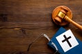 Catholic cross - catholicism religion concept - near gavel and book on wooden desk top view. Religious conflict concept