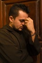 Catholic friar praying against a wooden door inside the basilica Cathedral